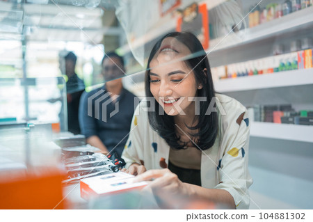 female seller smiling while picking the vape mod female seller smiling while picking the vape mod 104881302
