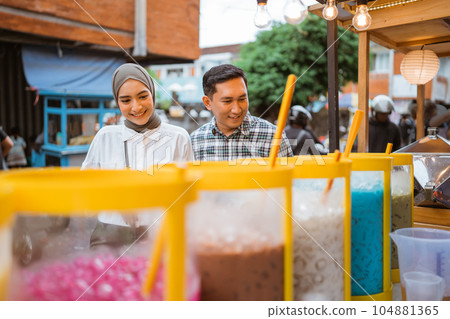 muslim couple buy drink from a street vendor muslim couple buy drink from a street vendor 104881365