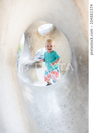 Child playing on outdoor playground. Toddler plays on school or kindergarten yard. Active kid on stone sculpured slide. Healthy summer activity for children. Little boy climbing outdoors 104881374