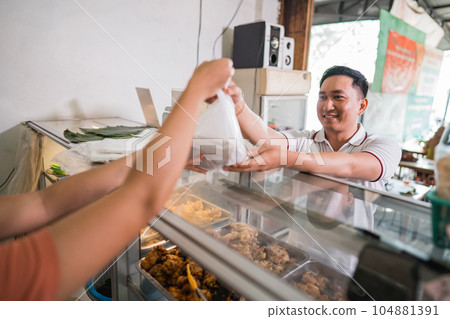 male customer receives a plastic of food from a vendor male customer receives a plastic of food from a vendor 104881391