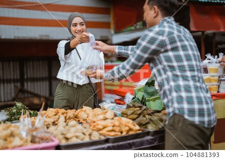 A beautiful girl wearing a headscarf selling a food stall on the side of the road gives takjil food A beautiful girl wearing a headscarf selling a food stall on the side of the road gives takjil food 104881393