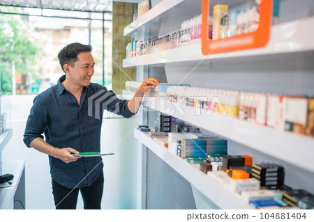 male shopkeeper holding the digital tablet while observing the liquid stock male shopkeeper holding the digital tablet while observing the liquid stock 104881404