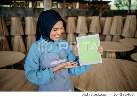 asian female entrepreneur in veil showing tablet screen to camera asian female entrepreneur in veil showing tablet screen to camera 104881406