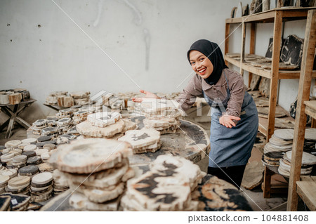 Asian woman in hijab smiling with hand gesture offering something Asian woman in hijab smiling with hand gesture offering something 104881408