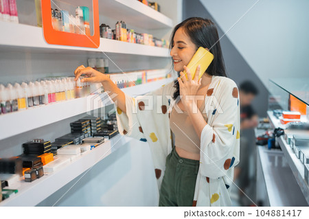 female shopkeeper calling on phone while arranging the liquid stock female shopkeeper calling on phone while arranging the liquid stock 104881417