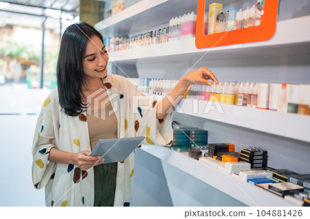 asian shopkeeper arranging the liquid stock at the shelf asian shopkeeper arranging the liquid stock at the shelf 104881426