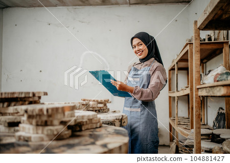 Asian veiled woman smiles at the camera holding a clipboard Asian veiled woman smiles at the camera holding a clipboard 104881427