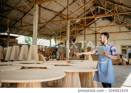 entrepreneurial man works in a woodcraft shop using a tablet entrepreneurial man works in a woodcraft shop using a tablet 104881429