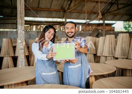 Asian business couple smiles as they show a tablet screen Asian business couple smiles as they show a tablet screen 104881445