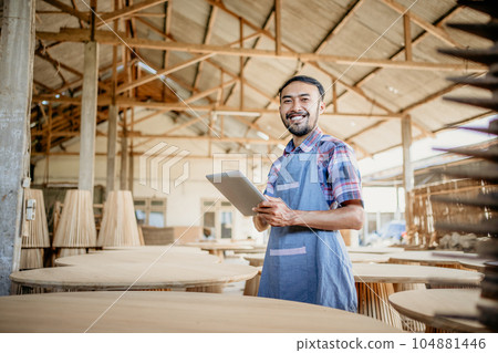 Asian entrepreneur man using tablet with wood craft shop in the background Asian entrepreneur man using tablet with wood craft shop in the background 104881446