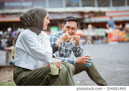 couple sitting on a road side enjoy the food from street vendor couple sitting on a road side enjoy the food from street vendor 104881460