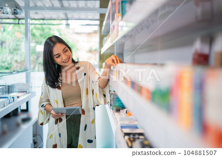 female shopkeeper holding the digital tablet while observing the liquid stock female shopkeeper holding the digital tablet while observing the liquid stock 104881507