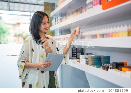 female shopkeeper smiling while checking the liquid stock at the vape store female shopkeeper smiling while checking the liquid stock at the vape store 104881509