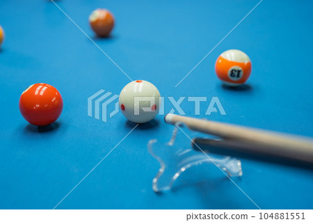 the cue stick poking the white ball helped by the bridge the cue stick poking the white ball helped by the bridge 104881551