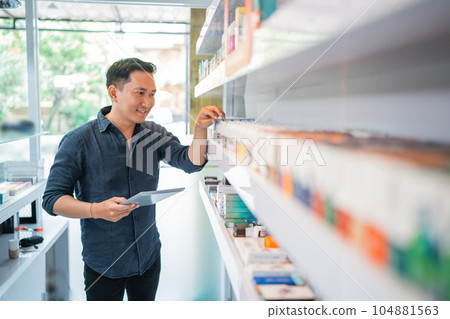 male shopkeeper checking the liquid stock at the shelf male shopkeeper checking the liquid stock at the shelf 104881563