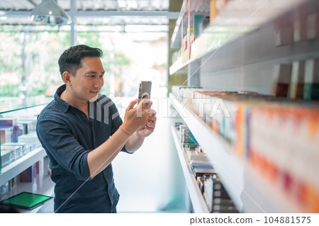 male shopkeeper taking photo of the liquid stock male shopkeeper taking photo of the liquid stock 104881575