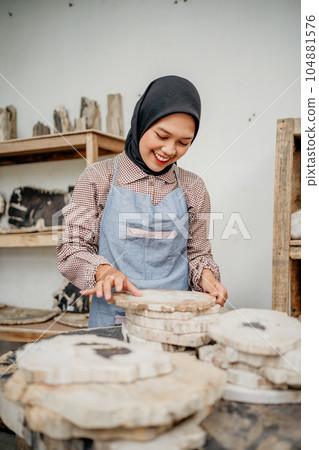 Asian veiled businesswoman holding a stone craft on a table Asian veiled businesswoman holding a stone craft on a table 104881576