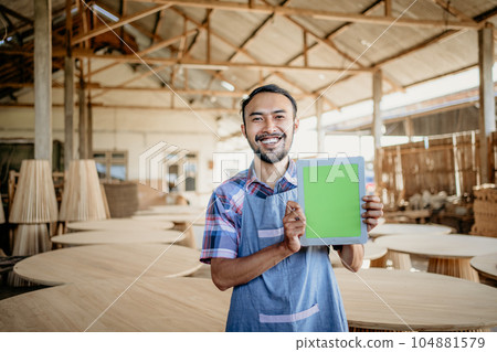 smiling Asian entrepreneur showing a blank screen to the camera smiling Asian entrepreneur showing a blank screen to the camera 104881579