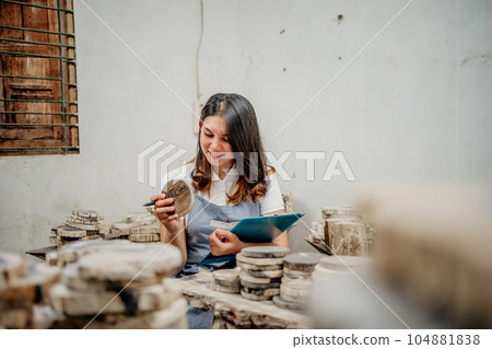 beautiful businesswoman holding a clipboard while checking craft stones beautiful businesswoman holding a clipboard while checking craft stones 104881838