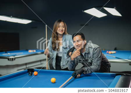 female pool player holding the cue stick while standing female pool player holding the cue stick while standing 104881917