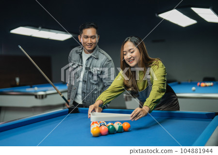 pool table worker helps player arranging the balls with triangle rack pool table worker helps player arranging the balls with triangle rack 104881944