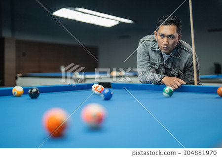 male billiard player poking the ball seriously using the cue stick 104881970