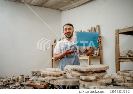 smiling male entrepreneur wearing apron with hands presenting something 104881982