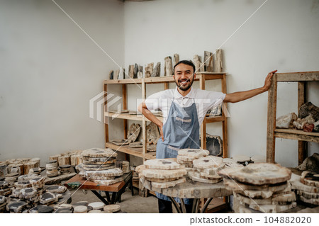 smiling male entrepreneur wearing an apron with his hands on his waist smiling male entrepreneur wearing an apron with his hands on his waist 104882020