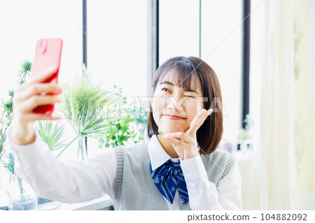 High school girl taking a selfie with a smartphone High school girl taking a selfie with a smartphone 104882092
