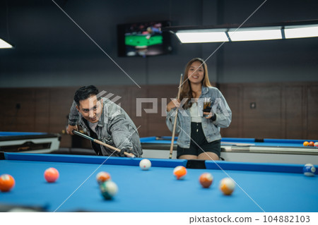 female player holding the glass while standing behind the male player 104882103