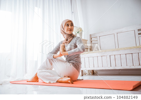 muslim woman instructor wearing hijab doing yoga pilates pose on mattress muslim woman instructor wearing hijab doing yoga pilates pose on mattress 104882149