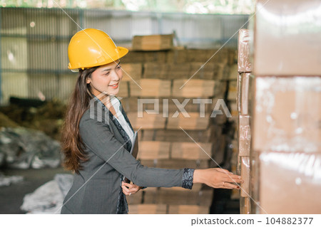 Young businesswoman checks goods in boxes at a factory Young businesswoman checks goods in boxes at a factory 104882377