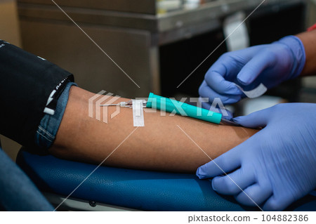 close up hand attaching needle to artery uring blood transfusion process 104882386