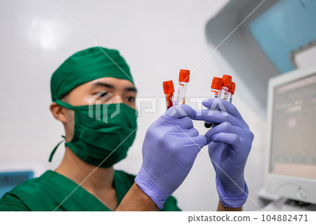 doctor wearing mask and gloves observing blood ampoule bottles 104882471