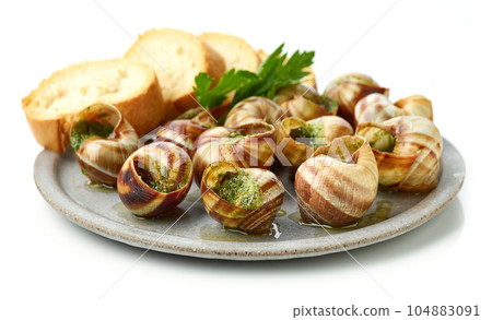 plate of baked escargot snails filled with parsley and garlic butter plate of baked escargot snails filled with parsley and garlic butter 104883091