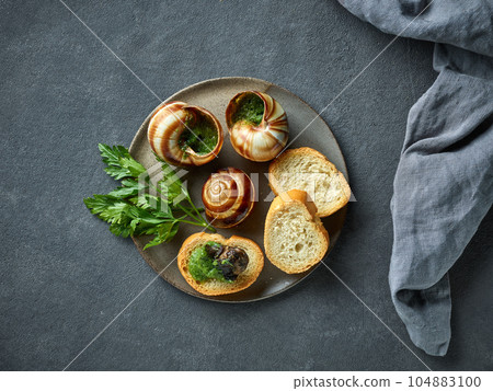 plate of baked escargot snails filled with parsley and garlic butter 104883100