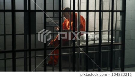 Elderly prisoner sits in prison cell in jail, eats food Elderly prisoner sits in prison cell in jail, eats food 104883215