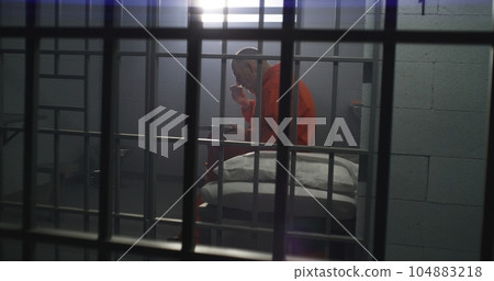 Elderly prisoner sits in prison cell in jail, eats food Elderly prisoner sits in prison cell in jail, eats food 104883218