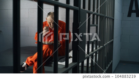 Elderly prisoner eats food sitting in prison cell in jail Elderly prisoner eats food sitting in prison cell in jail 104883219