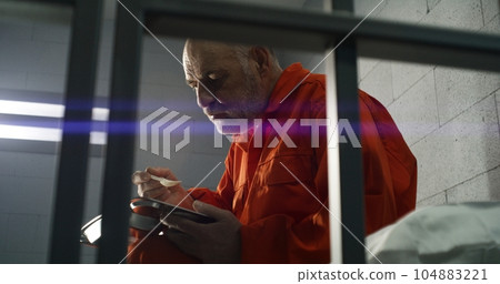 Elderly criminal eats dinner sitting in prison cell in jail Elderly criminal eats dinner sitting in prison cell in jail 104883221