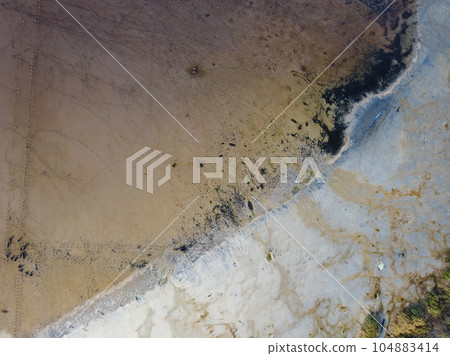 Human footprints create a striking pattern in the intricate texture of a swamp Human footprints create a striking pattern in the intricate texture of a swamp 104883414