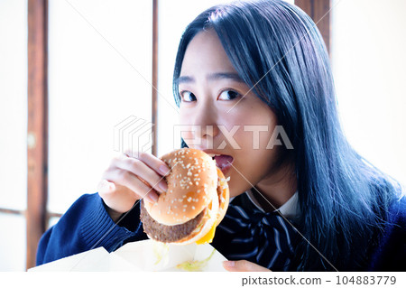 high school girl eating hamburger 104883779