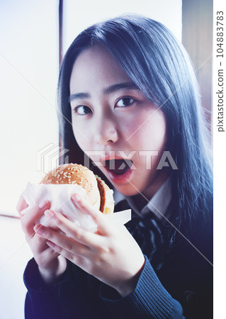 high school girl eating hamburger 104883783