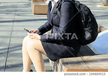 Businesswoman sitting on a bench with a backpack Businesswoman sitting on a bench with a backpack 104884513