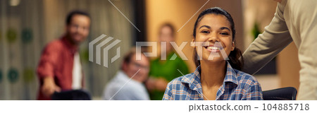 Two young multiracial colleagues looking at camera and smiling while working together on laptop in the modern office or coworking space 104885718