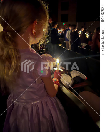 Caucasian girl in dress during a candle light church service. Caucasian girl in dress during a candle light church service. 104887923