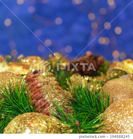 Shiny yellow Christmas balls and cone with barks and pine branches. Blue background with bokeh. New year card. Copy space Shiny yellow Christmas balls and cone with barks and pine branches. Blue background with bokeh. New year card. Copy space 104888245