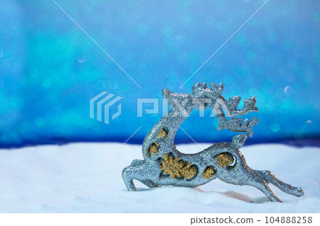 Merry Christmas toy deer on the snow and blue sky from behind. Blurred background. New year card. Copy space Merry Christmas toy deer on the snow and blue sky from behind. Blurred background. New year card. Copy space 104888258