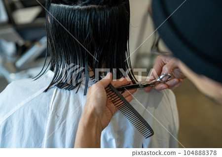 Woman getting a haircut at a beauty salon 104888378
