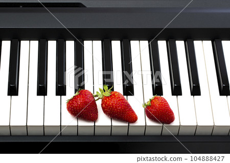 Three ripe strawberries on the piano keys 104888427